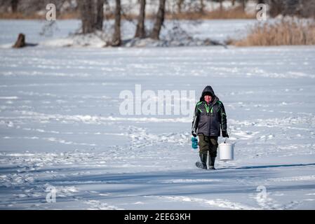 Zegrze, Pologne - 13 février 2021 : pêche sous la glace. Pêcheur à la ligne sur un lac gelé. Sports d'hiver. Les gens sur la glace. Banque D'Images