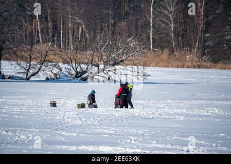 Zegrze, Pologne - 13 février 2021 : pêche sous la glace. Pêcheur à la ligne sur un lac gelé. Sports d'hiver. Les gens sur la glace. Banque D'Images