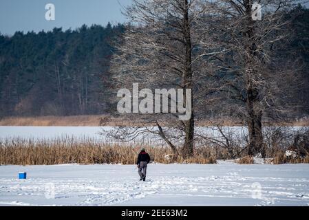 Zegrze, Pologne - 13 février 2021 : pêche sous la glace. Pêcheur à la ligne sur un lac gelé. Sports d'hiver. Les gens sur la glace. Banque D'Images