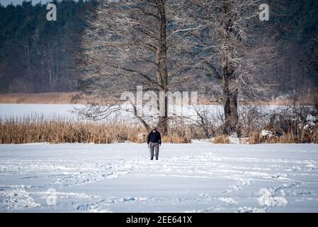 Zegrze, Pologne - 13 février 2021 : pêche sous la glace. Pêcheur à la ligne sur un lac gelé. Sports d'hiver. Les gens sur la glace. Banque D'Images