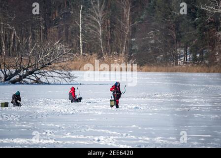 Zegrze, Pologne - 13 février 2021 : pêche sous la glace. Pêcheur à la ligne sur un lac gelé. Sports d'hiver. Les gens sur la glace. Banque D'Images