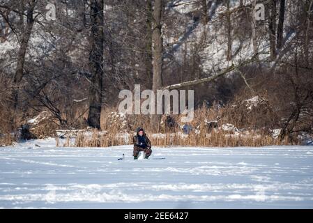 Zegrze, Pologne - 13 février 2021 : pêche sous la glace. Pêcheur à la ligne sur un lac gelé. Sports d'hiver. Les gens sur la glace. Banque D'Images