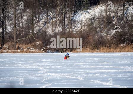 Zegrze, Pologne - 13 février 2021 : pêche sous la glace. Pêcheur à la ligne sur un lac gelé. Sports d'hiver. Les gens sur la glace. Banque D'Images