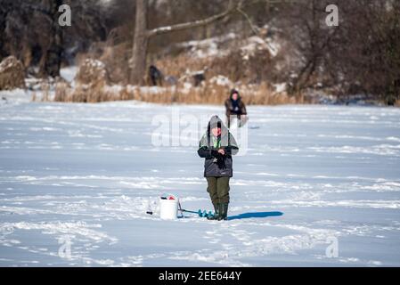 Zegrze, Pologne - 13 février 2021 : pêche sous la glace. Pêcheur à la ligne sur un lac gelé. Sports d'hiver. Les gens sur la glace. Banque D'Images