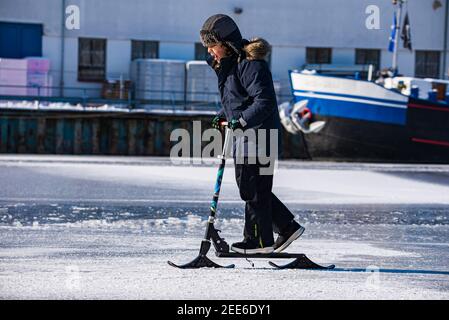 Prague, République tchèque - 14 février 2021. Jeune garçon en scooter avec patins sur glace Banque D'Images