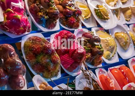 Marché aux fruits de rue en Thaïlande avec divers fruits exotiques frais: Mangousteen, rambutan, pomme rose dans des emballages en plastique Banque D'Images