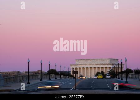 Le ciel devient rose pâle après le coucher du soleil, tandis que les voitures traversent le pont Arlington Memorial Bridge. Le Lincoln Memorial peut être vu dans l'arrière-gro Banque D'Images