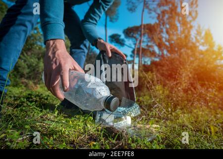 Homme nettoyant la forêt de déchets en plastique. Nettoyage de la nature. Bénévole Banque D'Images