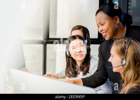 La sympathique femme d'affaires noire de formation de superviseur de travail à ses collègues multiethniques dans le bureau du centre d'appels Banque D'Images