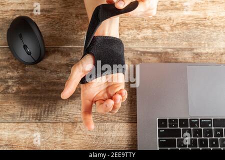 Un traumatisme chronique de l'articulation du poignet chez les personnes utilisant la souris d'ordinateur peut entraîner des troubles qui causent de l'inflammation et de la douleur. Une femme travaillant sur un bureau utilise Banque D'Images