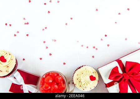 Boîtes-cadeaux avec bonbons en forme de coeur et cupcakes en velours rouge sur papier blanc, concepts de jour de la Saint-Valentin ou de mariage Banque D'Images