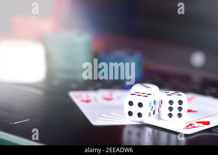 Plate-forme de jeu en ligne, casino et affaires de jeu. Cartes, dés et pièces de jeu multicolores sur le clavier de l'ordinateur portable. Banque D'Images