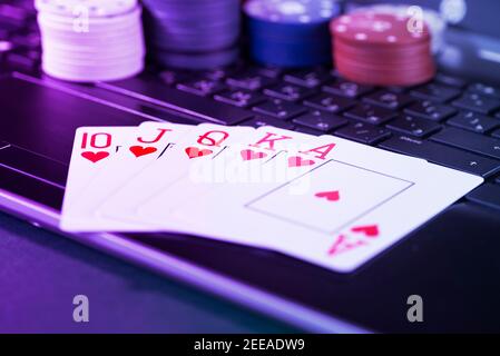Plate-forme de jeu en ligne, casino et affaires de jeu. Cartes, dés et pièces de jeu multicolores sur le clavier de l'ordinateur portable. Banque D'Images
