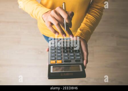 Femme entrepreneur utilisant une calculatrice avec un stylo dans sa main, calculant les dépenses financières au bureau à domicile Banque D'Images