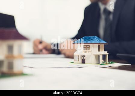 Document de signature de l'agent immobilier avec modèle de maison sur le tableau Banque D'Images