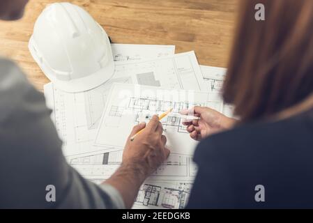 L'équipe d'architectes ou d'ingénieurs discute de la conception d'un projet à l'aide de plans au bureau avant de se rendre sur le chantier. Banque D'Images