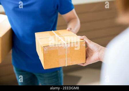 Un homme dans une chemise bleue livrant une porte à livraison de colis de porte à une femme Banque D'Images