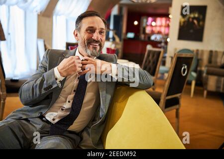 Homme joyeux dans un costume chic qui ajuste son style Banque D'Images