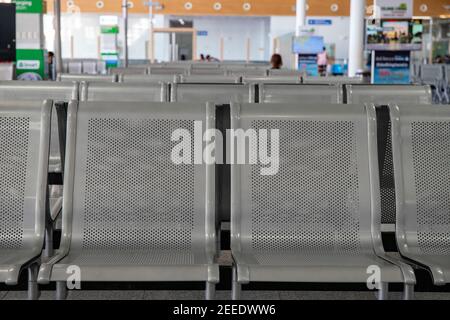 Rangée de chaises métallique pour les clients d'aéroport, avec publicité floue sur fond. Intérieur de l'aéroport sans passagers. Chaises de réception dans un public Banque D'Images