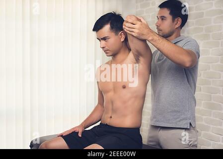 Entraînement thérapeute exercice de réadaptation, étirement de tricep de tête, à l'athlète homme patient à l'hôpital - concept de physiothérapie Banque D'Images