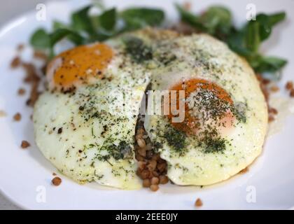 Œuf frit avec sarrasin et arugula sur une assiette blanche Banque D'Images