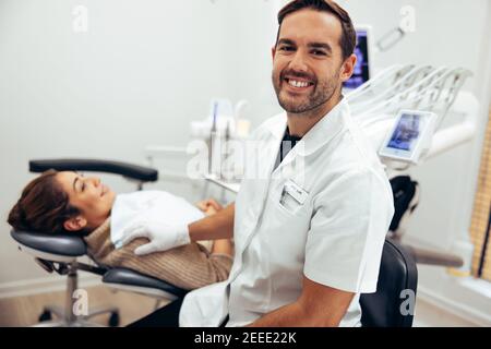 Dentiste masculin réussi dans sa clinique. Expert dentaire chez une patiente en dentisterie. Banque D'Images