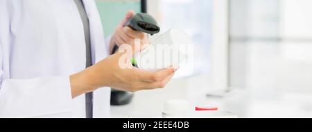 Pharmacien lisant un flacon de médicament avec lecteur de code-barres en pharmacie - bannière web panoramique Banque D'Images