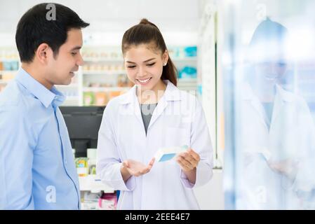 Une pharmacienne tient une bouteille de médicament donnant des conseils au client pharmacie ou pharmacie Banque D'Images