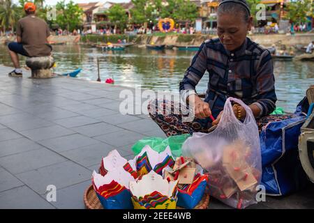 Hoi an, Vietnam - 28 juillet 2019 : vieille femme faisant des bougies flottantes. Portrait du peuple vietnamien. Photo de voyage en Asie du Sud. Vendeur de souvenirs sur le travail. Nuit Banque D'Images