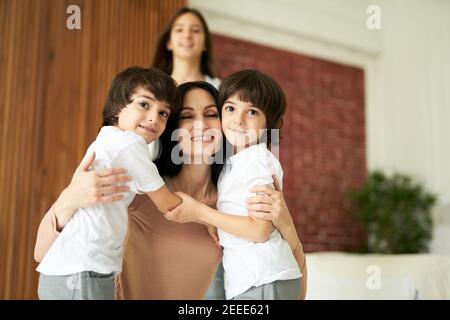 Portrait d'enfants latins mignons, petits garçons jumeaux regardant l'appareil photo et embrassant leur mère, passant du temps ensemble à la maison. Famille, concept d'enfance Banque D'Images