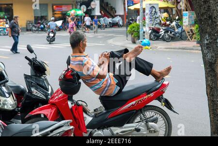 Hoi an, Vietnam - 28 juillet 2019: Homme prenant le repos sur moto. Pilote de scooter avec smartphone en mains. Temps passé avec l'Internet mobile. Asie du Sud p Banque D'Images