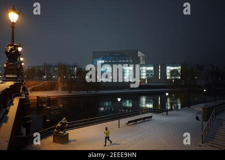 Berlin, Allemagne. 16 février 2021. Un jogger longe les rives de la Spree en début de matinée sur la neige fraîche à la vue de la chancellerie fédérale. Credit: Jörg Carstensen/dpa/Alay Live News Banque D'Images