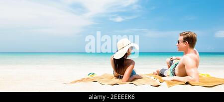 Couple allongé sur une plage de sable blanc relaxant et prenant un bain de soleil pendant les vacances d'été - bannière web panoramique avec copie espace Banque D'Images