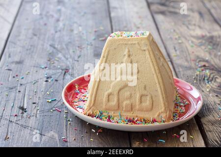 Dessert traditionnel russe au fromage cottage de Pâques, Paskha orthodoxe, avec du lait concentré bouilli et des noix arrosées de garniture de sucre sur une table en bois Banque D'Images