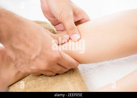 Mains d'un thérapeute masculin (masseur) donnant un massage à une femme jambe Banque D'Images