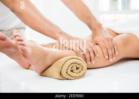 Mains d'un thérapeute masculin (masseur) donnant un massage à une femme jambe Banque D'Images