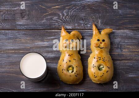 Patties avec oignons verts et oeuf, sous forme de lapin sur une table en bois avec un verre de lait, espace libre. Délicieux petit déjeuner maison pour les enfants Banque D'Images