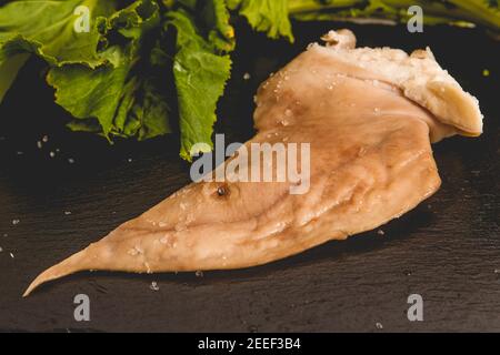 oreille de porc salée et fumée sur plaque d'ardoise avec navet verts en arrière-plan Banque D'Images