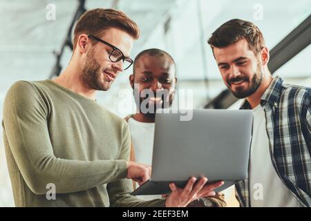 Jeunes professionnels de sexe masculin regardant quelque chose sur l'écran d'un ordinateur portable Banque D'Images