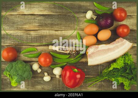 Des œufs de poulet frais et du balyk avec des légumes sont disposés sur la table. Sur la table sont des produits pour les oeufs avec du bacon et des légumes. Espace pour te Banque D'Images
