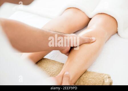 Thérapeute masculin (masseur) offrant un massage des jambes à une femme spa Banque D'Images