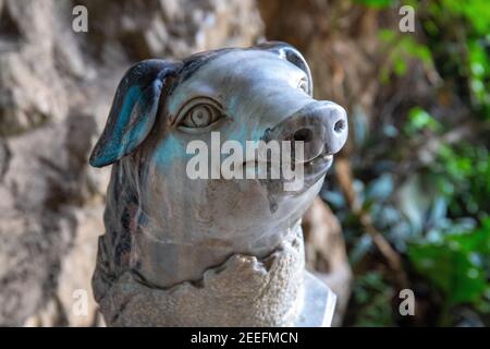 Statue en pierre de porc sculptée sur fond de jardin vert. Sculpture d'animaux de zodiaque chinois. Art asiatique traditionnel. Statue de sanglier en marbre à proximité du museau. Par Banque D'Images