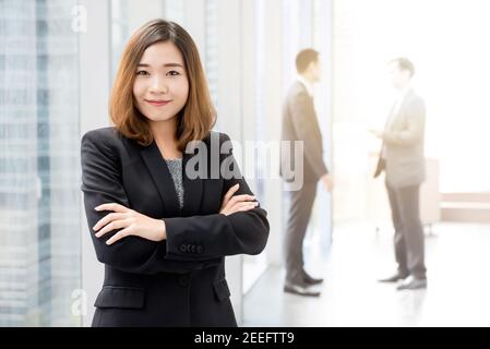 Femme d'affaires asiatique confiante debout et traversant les bras hall de l'immeuble de bureaux Banque D'Images