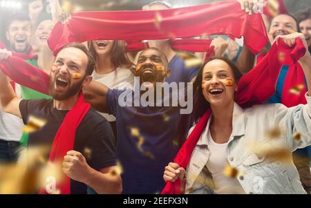 Football américain, les fans de football applaudissent leur équipe avec des foulards rouges au stade. Les fans enthousiastes applaudissent un but, soutenant les joueurs favoris. Concept de sport, émotions humaines, divertissement. Banque D'Images