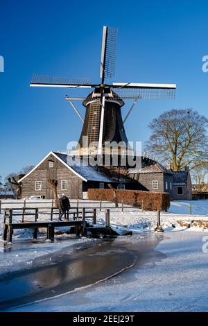 Pelmolen Ter Horst, Rijssen couvert d'un paysage enneigé Overijssel pays-Bas, moulin à vent historique pendant l'hiver. ancien moulin à vent en bois en Hollande, couple hommes et femme marchant dans la neige Banque D'Images