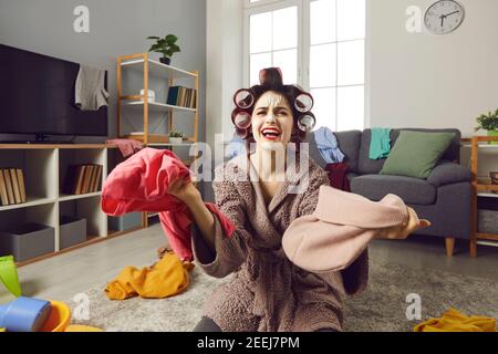 Une jeune femme au foyer fatiguée nettoie sa maison désordonnée et se plaint sur le chaos constant Banque D'Images