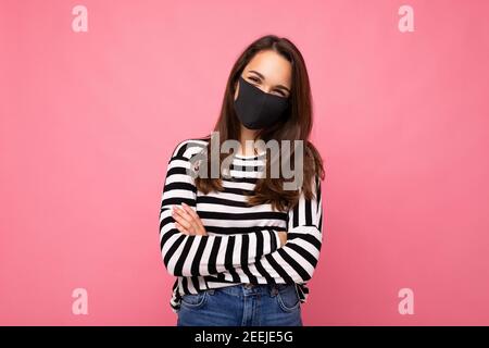 Jeune femme portant un masque anti-virus pour prévenir D'autres de l'infection corona COVID-19 et du cov 2 du SRAS ont été isolés sur fond rose Banque D'Images