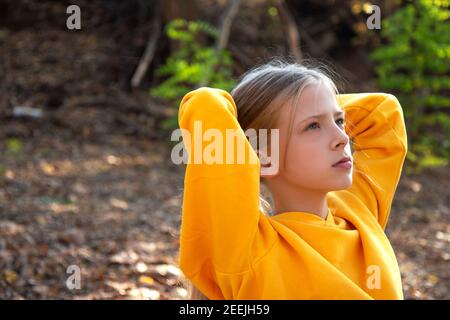 Belle jeune fille blonde dans un sweat-shirt orange vif et jeans dans un parc d'automne. Portrait d'automne dans la forêt Banque D'Images