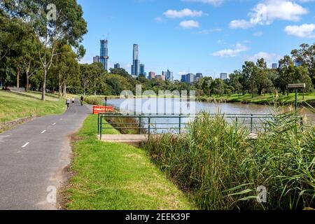 Les personnes s'exerçant sur un chemin le long de la Yarra River avec Avec de hauts bâtiments de Melboure en arrière-plan Banque D'Images