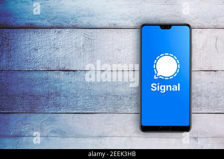 Smartphone avec logo de l'application de communication sociale signal à l'écran. Bureau en bois blanc, vue de dessus et espace de copie vide pour le texte de l'éditeur. Banque D'Images